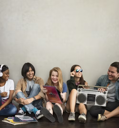 A group of young people casually sitting on the floor with music and books, representing relaxed community gatherings.