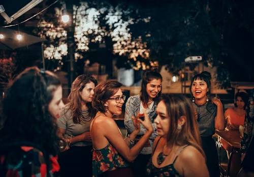 A group of women talking and laughing at night, representing intimate social connections.