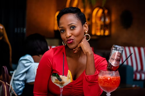 A woman with a seductive gaze holding a cocktail, symbolizing temptation and allure.