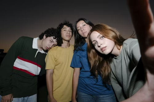 Four young people with serious expressions, representing raw and unfiltered performance.