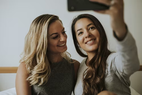 Two smiling women taking a selfie, representing positive community interaction.